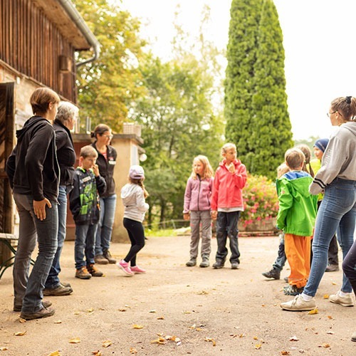 Eine Gruppe von Kindern und Erwachsenen stehen zu einer Besprechung im Kreis