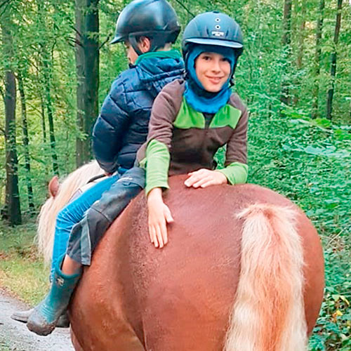 Zwei Jungen reiten auf einem Pferd